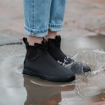 model wearing knit waterproof boots in a puddle