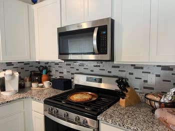 A modern kitchen with stainless steel appliances and the marble tile on the back splash