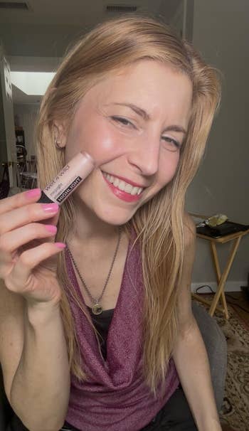 Person smiling and holding a lipstick conduit labeled
