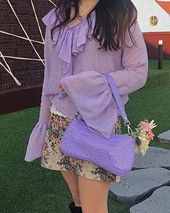 a model posing with the purple bag