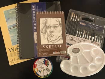 a reviewer showing the sketch pads, brushes, and palette that come with the set