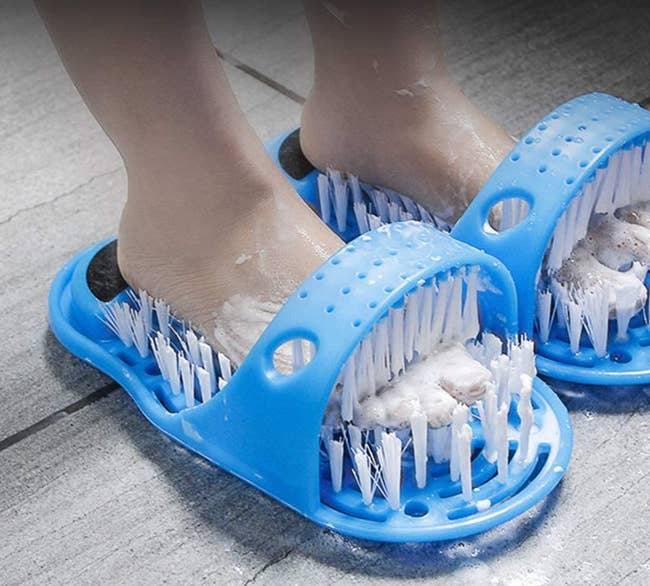 Model with feet inside of a blue bristle slipper-shaped scrubber 