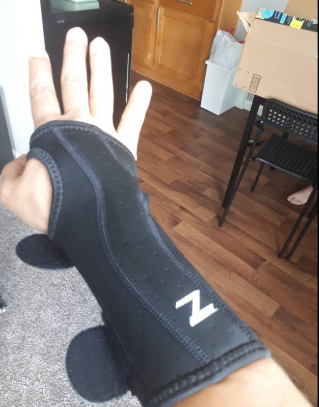 Reviewer in black brace that extends from mid forearm to the upper hand with cutouts for fingers 