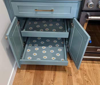 Kitchen cabinet with open drawer revealing daisy pattern lining, hinting at home organization products