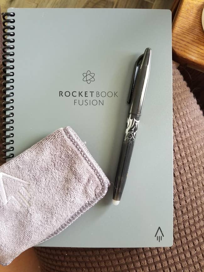 reviewer's light blue Rocketbook planner with pen and cleaning cloth