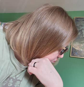 Person with chin-length hairsbreadth and glasses successful profile, wearing a casual greenish graphic t-shirt and a ring, sitting successful a country with art