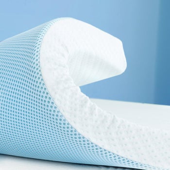 the curled up edge of a gel-infused mattress topper with a white, thick top and a blue, thinner base