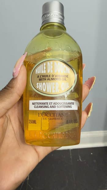 Person holding a 250ml L'Occitane almond ablution oil