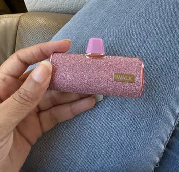 another reviewer holding up the shiny pink portable battery