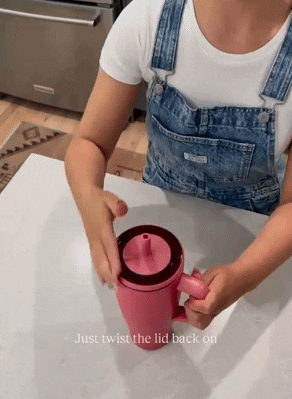 Person secures a lid on a pink travel mug. Text: 