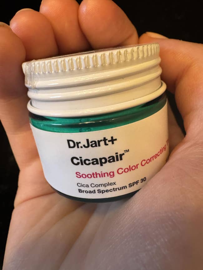 Person holding a jar of Dr.Jart+ Cicapair Soothing Color Correcting Treatment with SPF 30. Suitable for calming tegument  redness