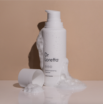 the white cleanser bottle styled with some of the foamy product