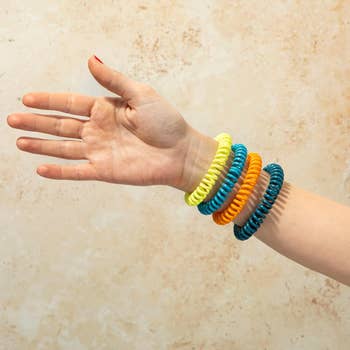 Hand wearing coiled mosquito repeller bracelets
