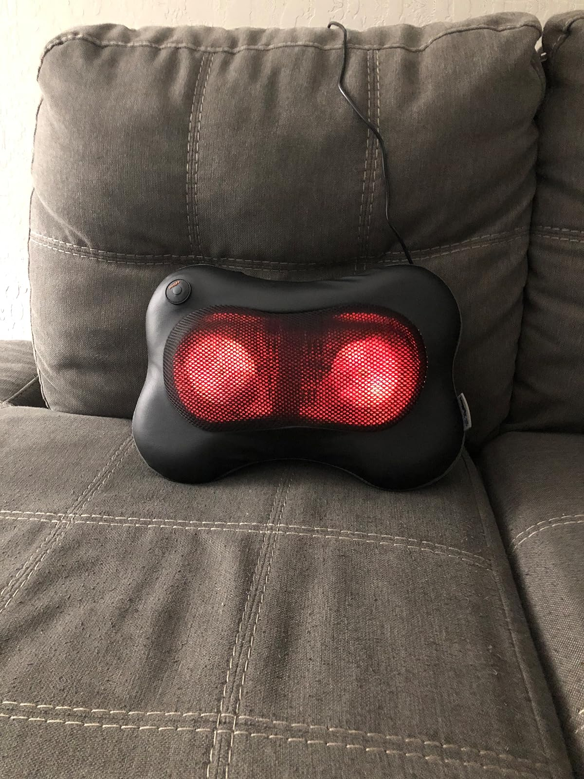 an illuminated massage pillow sitting connected  a sofa  