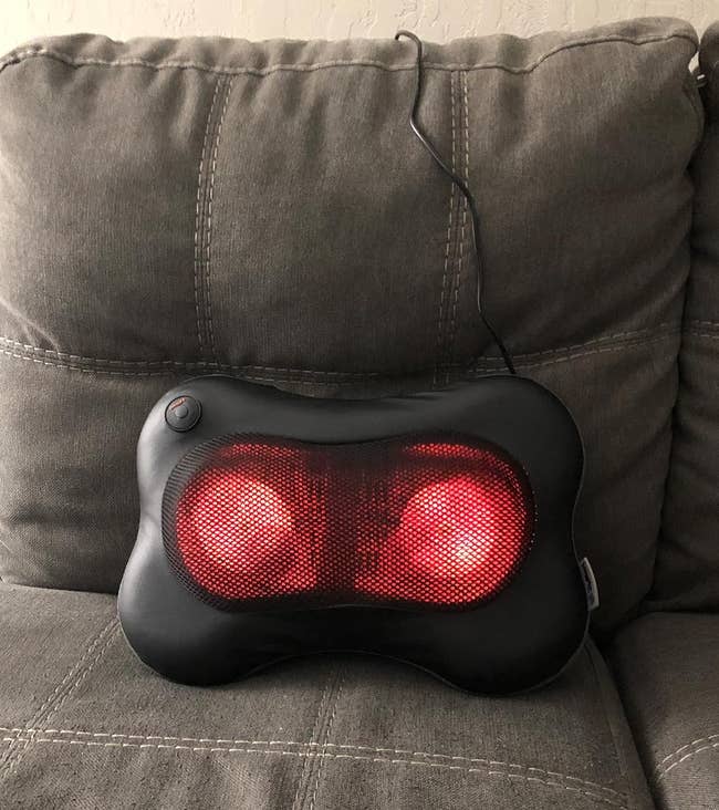 an illuminated massage pillow sitting connected a sofa