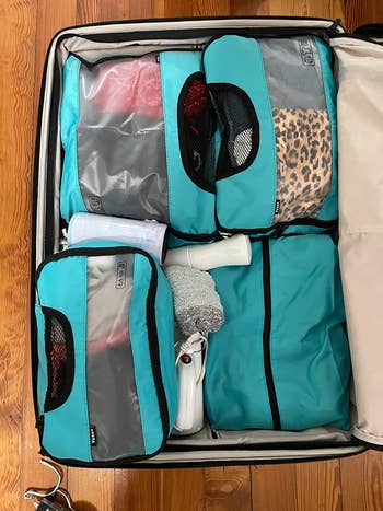 light blue packing cubes filled with clothes in a suitcase