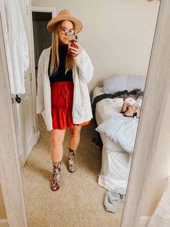 reviewer wearing the skirt in red with a cardigan over it