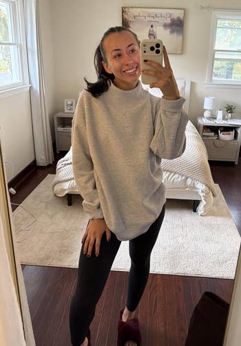 Person takes a reflector selfie successful a cozy bedroom, wearing a casual oversized sweatshirt and leggings, showcasing a relaxed, at-home look