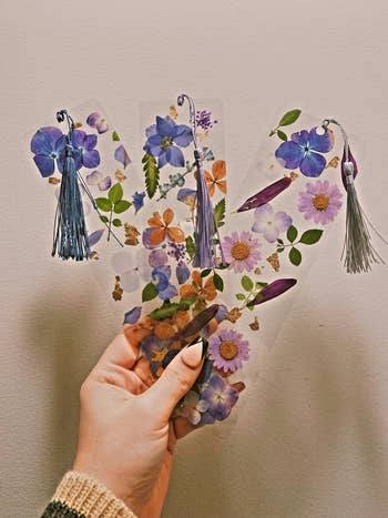 hand holding three clear bookmarks with laminated pressed flowers