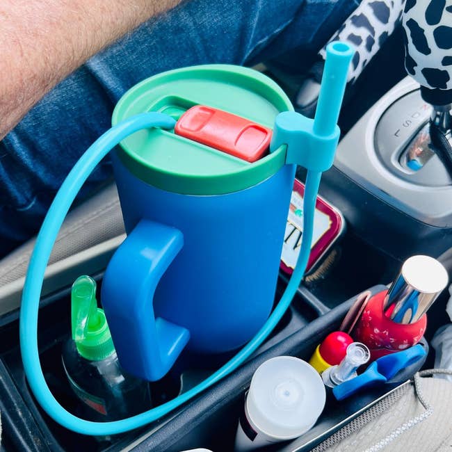 Cangkir berinsulasi besar dengan sedotan internal ditempatkan di tempat cangkir mobil. Pemegangnya juga berisi berbagai barang termasuk pembersih, lipstik, dan produk perawatan pribadi lainnya