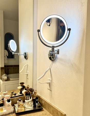 reviewer photo of lit wall mounted makeup mirror in the bathroom