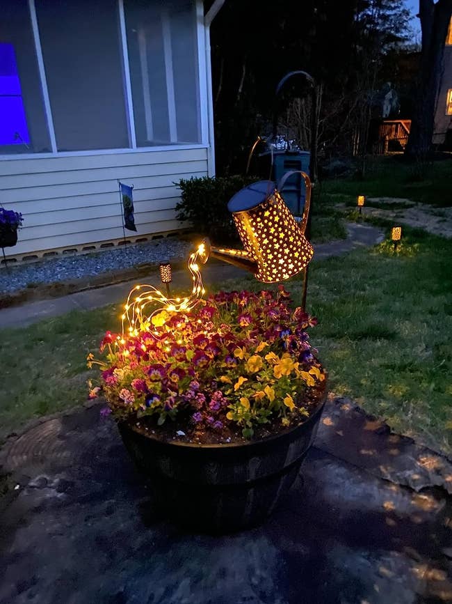 reviewer image of the hanging watering can and LED lights pouring into a flower pot