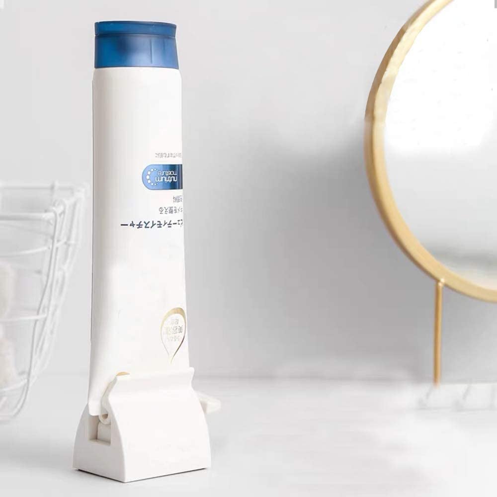 the toothpaste holder holding the bottom of an upright tube of toothpaste on a bathroom counter
