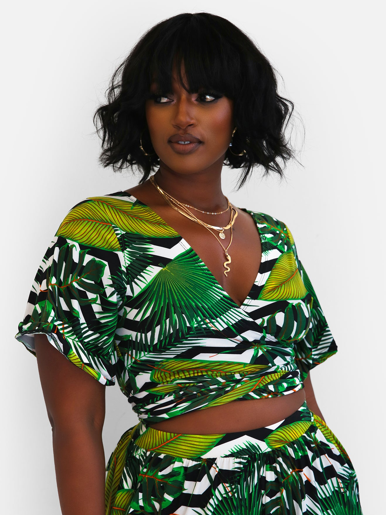 a model wearing the wrap crop top, which features a black and white chevron print overlaid with a palm print 