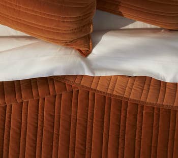 the velvet quilt in bourbon on a bed with white sheets