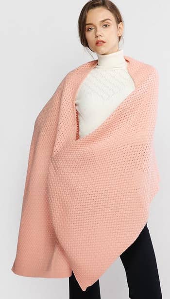 Woman in a white top, draped with a pink knit shawl, for a shopping feature