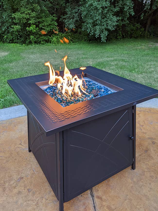 reviewer's fire pit lit up on their patio