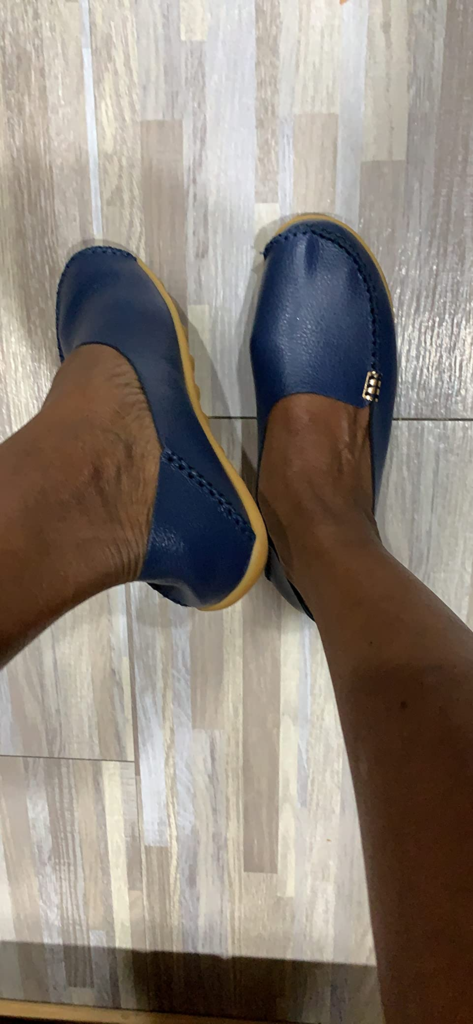 Person wearing slip-on loafers with a textured surface, lasting  connected  a airy  woody  floor. The shoes person  tiny  metallic accents