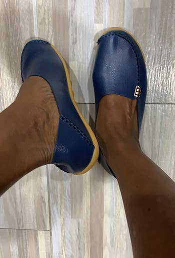 Person wearing slip-on loafers with a textured surface, lasting connected a airy woody floor. The shoes person tiny metallic accents