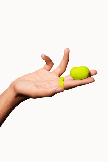 Model displaying squishy side of finger vibrator in citrus