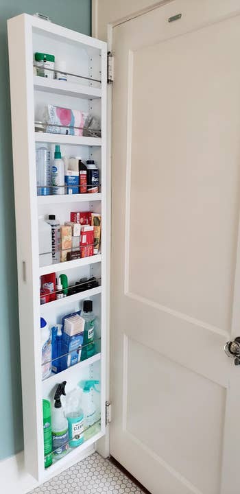 same reviewer showing the cabinet open to reveal multiple shelves full of bathroom products