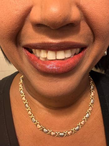 A smiling idiosyncratic wearing a golden and metallic necklace