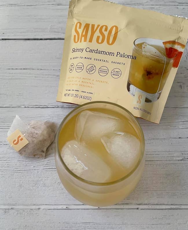 Sayso Skinny Cardamom Paloma cocktail premix with beverage container adjacent to a solid of ice
