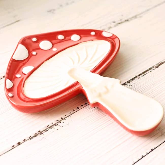 Ceramic spoon rest shaped like a mushroom with a red cap and white dots on it
