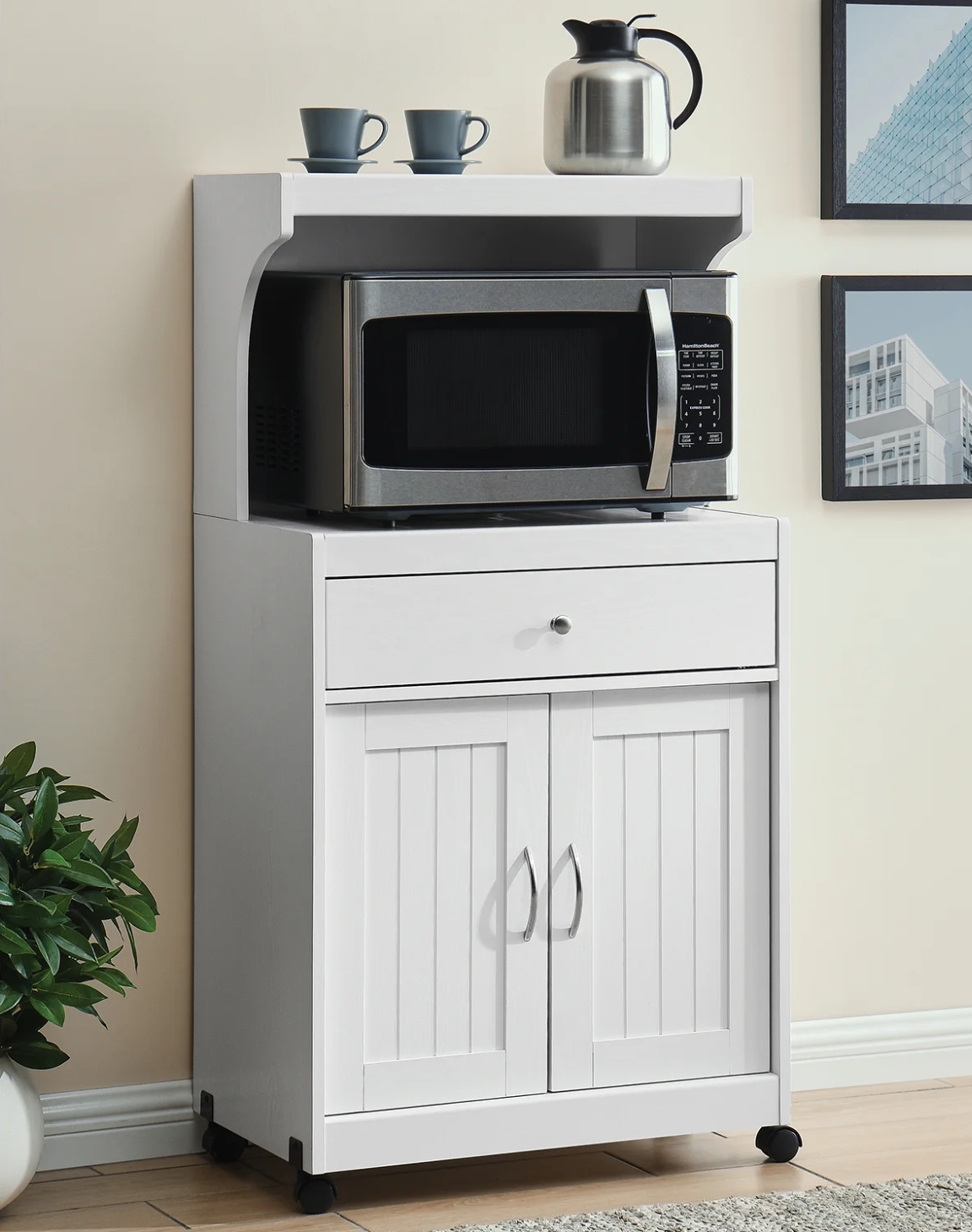 White microwave cart with cabinet, nook, and top shelf storing microwave and two mugs and coffee container