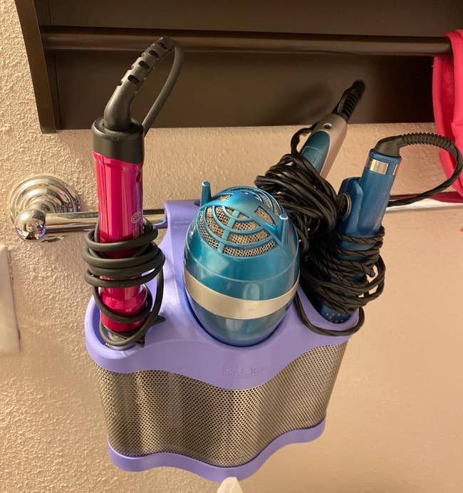 reviewer's periwinkle and silver styling station holding hair tools and hanging from a towel rack