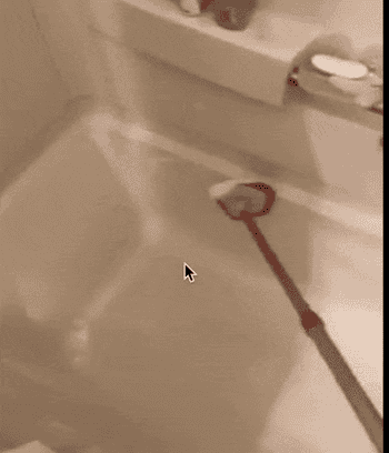 Reviewer using the scrubber with a pole to clean a tub 