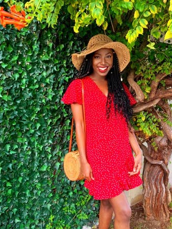 reviewer wearing dress in red with hat and matching purse