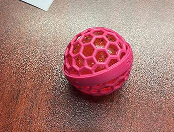 a reviewer photo of the purse cleaner ball with the outer plastic cage attached 