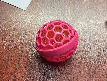 a reviewer photo of the purse cleaner ball with the outer plastic cage attached 