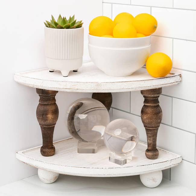Corner shelf with a plant, bowl of lemons, and two clear decorative spheres. Home decor inspiration