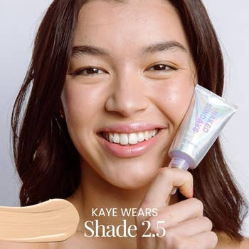 Person smiling portion holding a conduit of Naked Sundays product, Shade 2.5