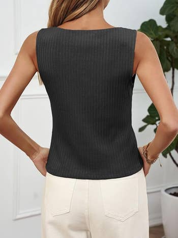 Person wearing a ribbed sleeveless apical and achromatic pants, lasting with hands connected hips successful a modern country with greenery