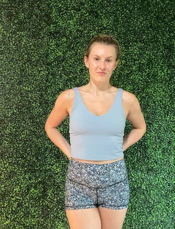 reviewer in a denim blue longline sports bra and patterned workout shorts
