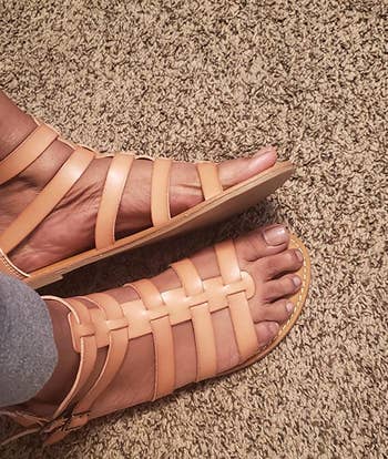 Reviewer wearing tan gladiator sandals with zipper back on carpet