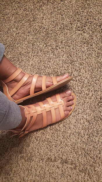 Reviewer wearing tan gladiator sandals with zipper back on carpet